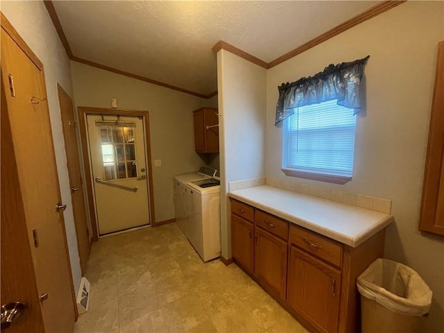 washroom featuring cabinet space, crown molding, a textured ceiling, and washing machine and clothes dryer