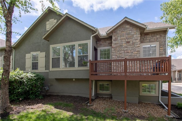 rear view of property with stone siding, a wooden deck, and stucco siding