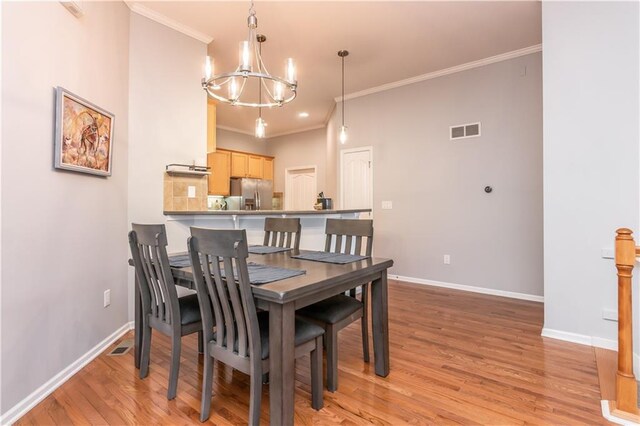 dining room with a chandelier, baseboards, crown molding, and light wood-style floors