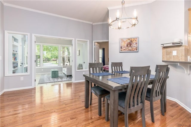 dining area with a chandelier, ornamental molding, light wood finished floors, and baseboards