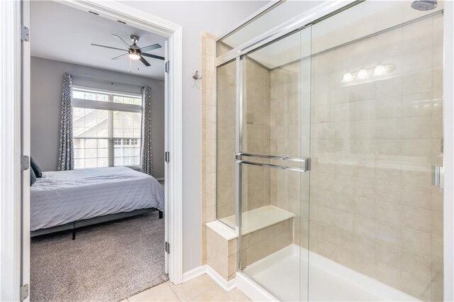 ensuite bathroom featuring a shower stall, a ceiling fan, tile patterned flooring, and baseboards
