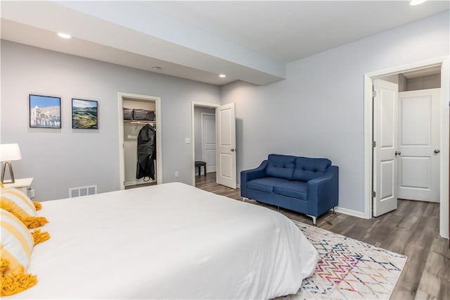 bedroom with wood finished floors, recessed lighting, baseboards, a walk in closet, and a closet