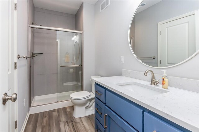 bathroom with toilet, a stall shower, vanity, and wood finished floors