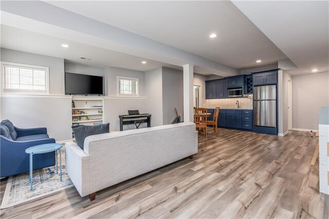 living area with light wood-type flooring, recessed lighting, and baseboards