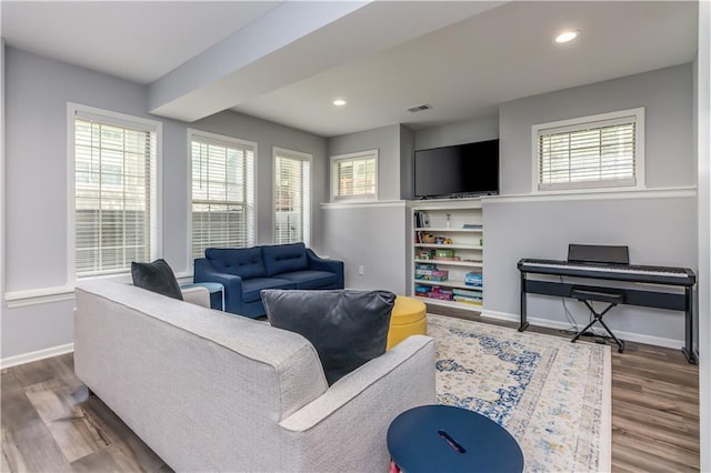 living area with baseboards, plenty of natural light, wood finished floors, and recessed lighting