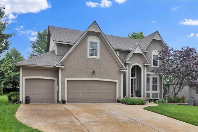 21511 W 100th Ter, Lenexa, KS 66220 - traditional home featuring stucco siding, a shingled roof, driveway, an attached garage, and a front lawn