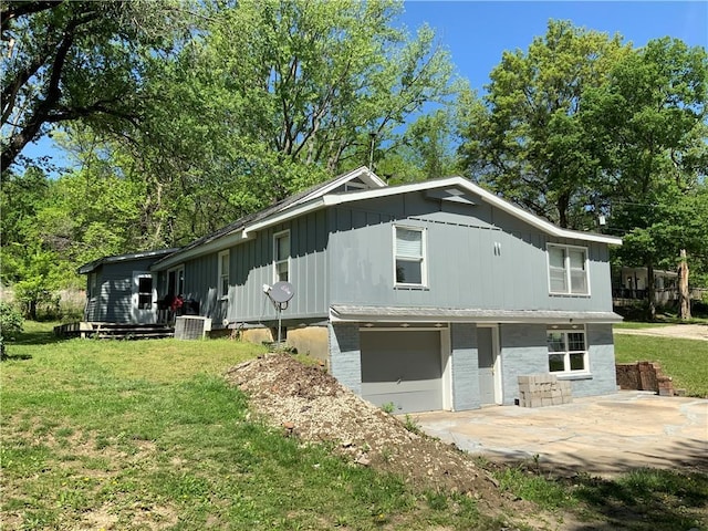 8480 NW High St Unit B, Amsterdam, MO 64723 - view of side of home featuring an attached garage, board and batten siding, central AC unit, concrete driveway, and a yard