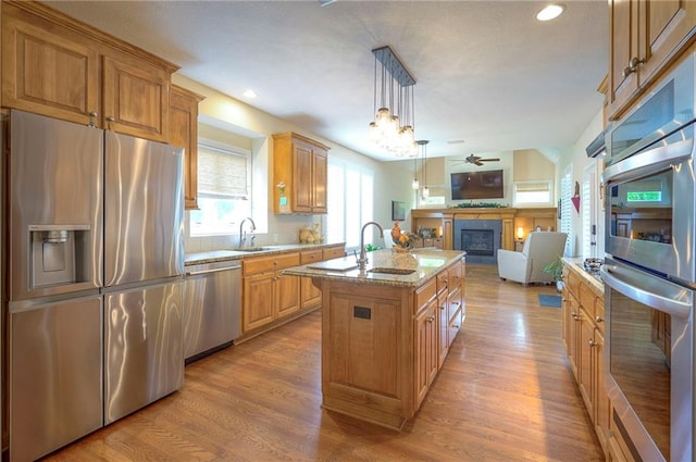 2945 W 143rd Ter, Leawood, KS 66224 - kitchen with appliances with stainless steel finishes, a fireplace, open floor plan, a sink, and a ceiling fan