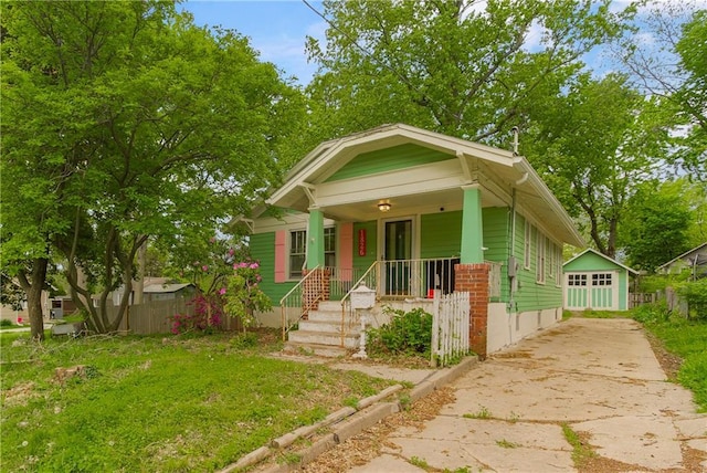 bungalow-style home featuring fence, an outdoor structure, concrete driveway, and a porch
