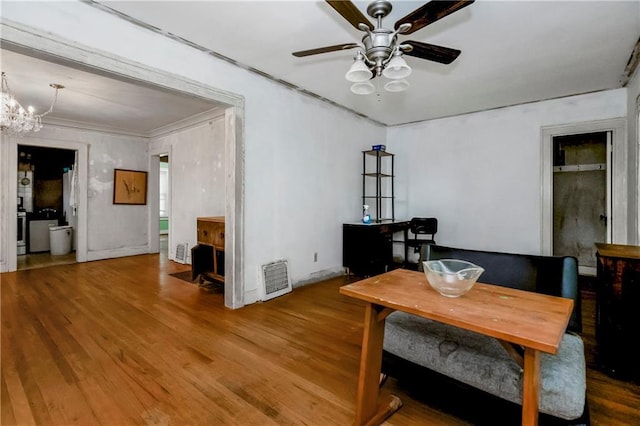 dining room with crown molding, ceiling fan with notable chandelier, baseboards, wood finished floors, and visible vents