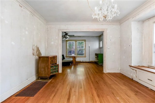unfurnished living room featuring visible vents, baseboards, crown molding, and wood finished floors