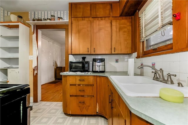kitchen with brown cabinets, a sink, light countertops, light floors, and backsplash