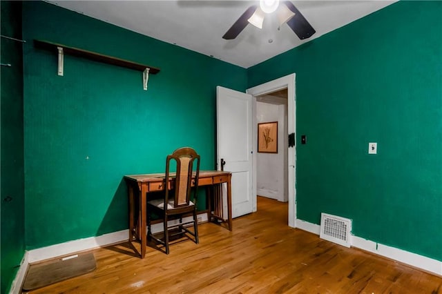 office space with baseboards, ceiling fan, wood finished floors, and visible vents