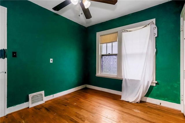 spare room featuring baseboards, ceiling fan, wood finished floors, and visible vents