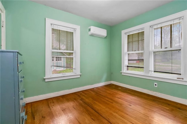 empty room featuring wood-type flooring, an AC wall unit, and baseboards