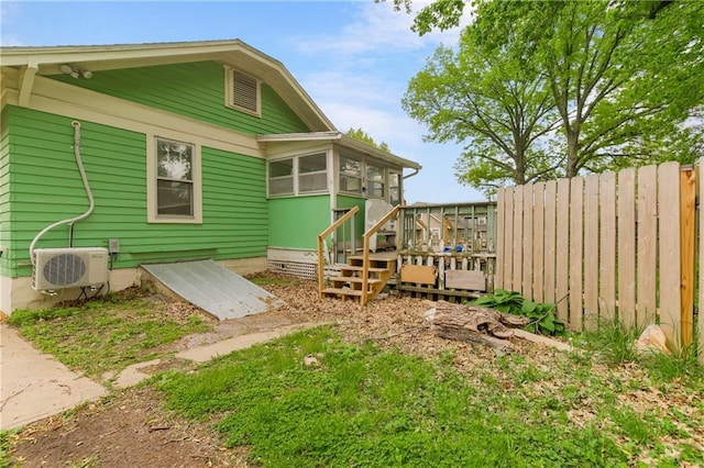 rear view of house featuring a sunroom, ac unit, a wooden deck, and fence