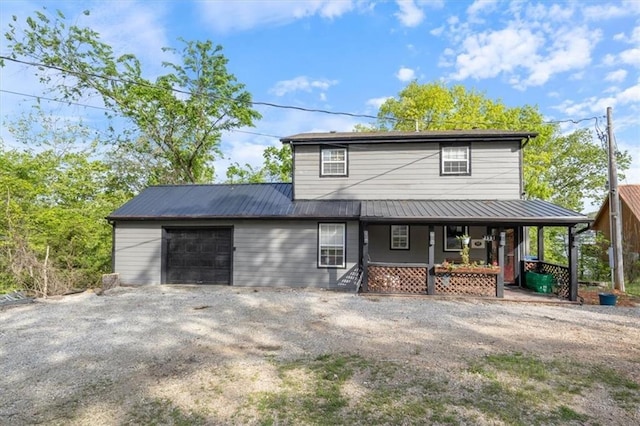 view of front of home with metal roof, a porch, an attached garage, and driveway