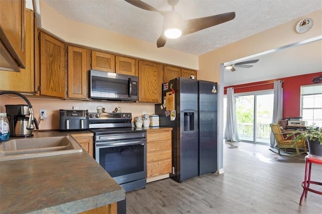kitchen featuring a ceiling fan, brown cabinetry, appliances with stainless steel finishes, and a textured ceiling