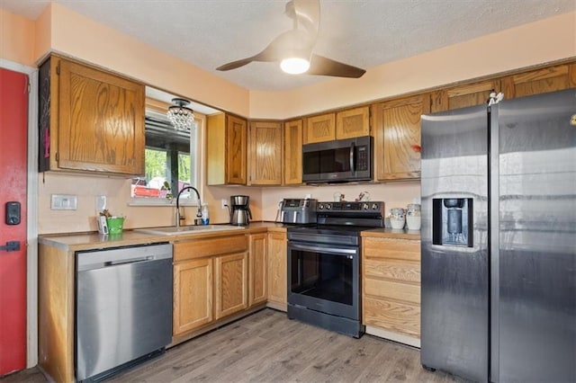 kitchen with ceiling fan, light wood-type flooring, a textured ceiling, a sink, and appliances with stainless steel finishes