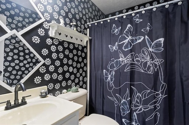 full bathroom featuring a textured ceiling, curtained shower, vanity, toilet, and wallpapered walls