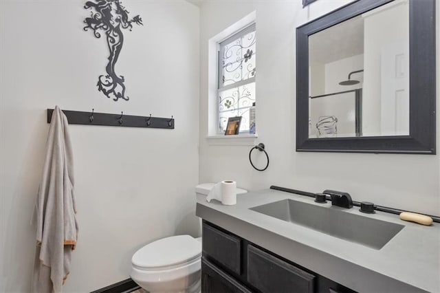 bathroom featuring vanity, walk in shower, and toilet
