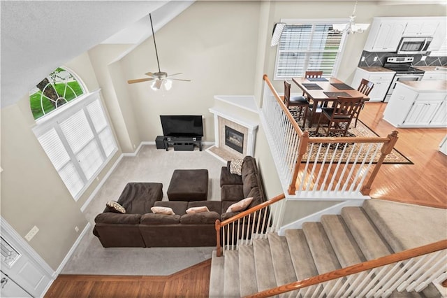 18461 W 157th St, Olathe, KS 66062 - living room featuring a ceiling fan, high vaulted ceiling, a chandelier, a glass covered fireplace, and light wood-style floors