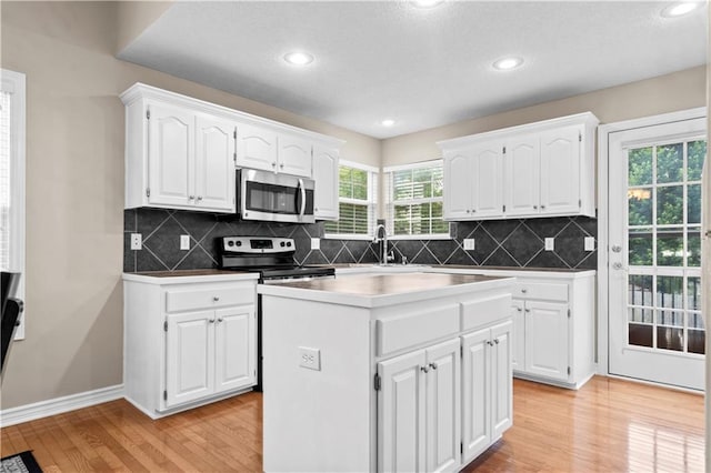 18461 W 157th St, Olathe, KS 66062 - kitchen featuring stainless steel appliances, light wood-style floors, white cabinets, a center island, and tasteful backsplash