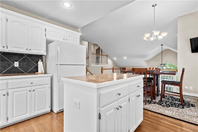 18461 W 157th St, Olathe, KS 66062 - kitchen featuring freestanding refrigerator, a chandelier, light wood-type flooring, a kitchen island, and vaulted ceiling