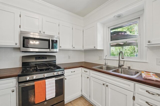 8020 Yecker Ave, Kansas City, KS 66109 - kitchen featuring stainless steel appliances, a sink, butcher block counters, white cabinetry, and crown molding