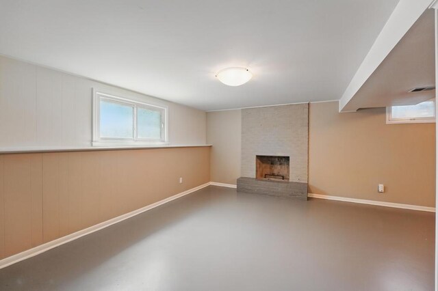 8020 Yecker Ave, Kansas City, KS 66109 - unfurnished living room featuring healthy amount of natural light, a brick fireplace, baseboards, and concrete flooring