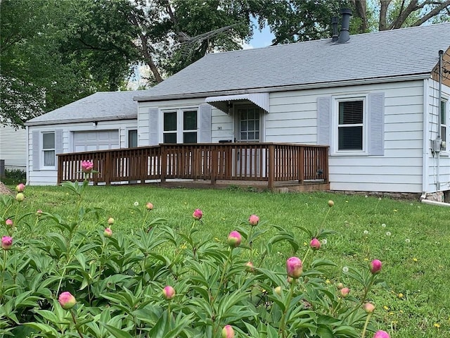 rear view of property featuring a deck, a yard, and roof with shingles