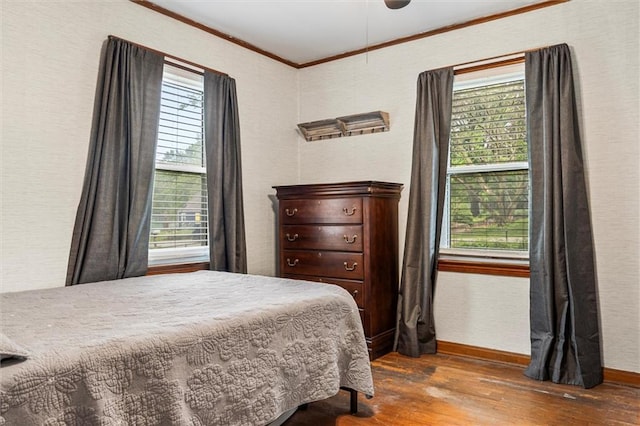 bedroom featuring wood finished floors, multiple windows, ornamental molding, baseboards, and a ceiling fan