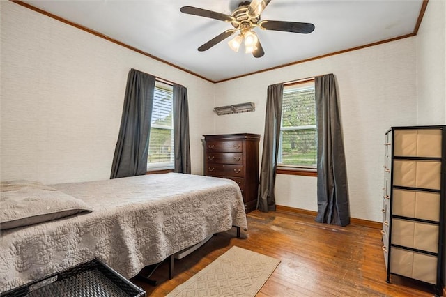 bedroom featuring ornamental molding, multiple windows, hardwood / wood-style floors, baseboards, and a ceiling fan