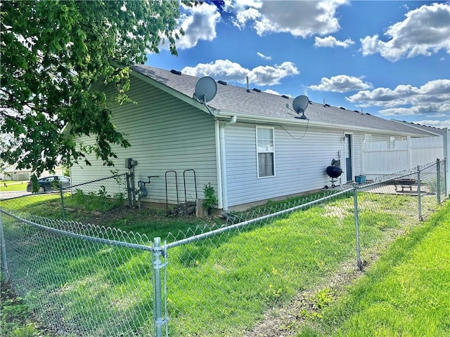view of home's exterior featuring a shingled roof, a lawn, and a fenced backyard