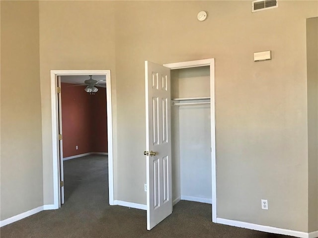 unfurnished bedroom featuring baseboards, a closet, dark colored carpet, and visible vents