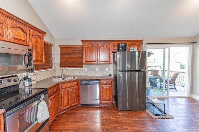 8115 NE 112th St, Kansas City, MO 64157 - kitchen with stainless steel appliances, a sink, vaulted ceiling, brown cabinetry, and dark wood finished floors