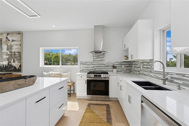 10924 W 67th St, Shawnee, KS 66203 - kitchen with stainless steel appliances, a sink, wall chimney exhaust hood, white cabinetry, and healthy amount of natural light