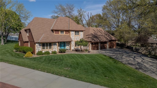 tudor home featuring concrete driveway, a front yard, and an attached garage