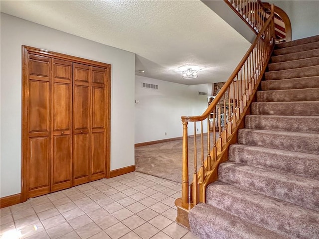 stairs with baseboards, a textured ceiling, tile patterned flooring, and carpet flooring