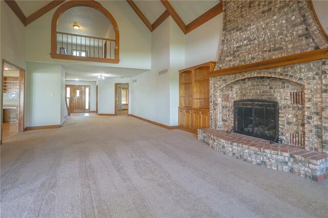 unfurnished living room with carpet, high vaulted ceiling, baseboards, a brick fireplace, and beamed ceiling