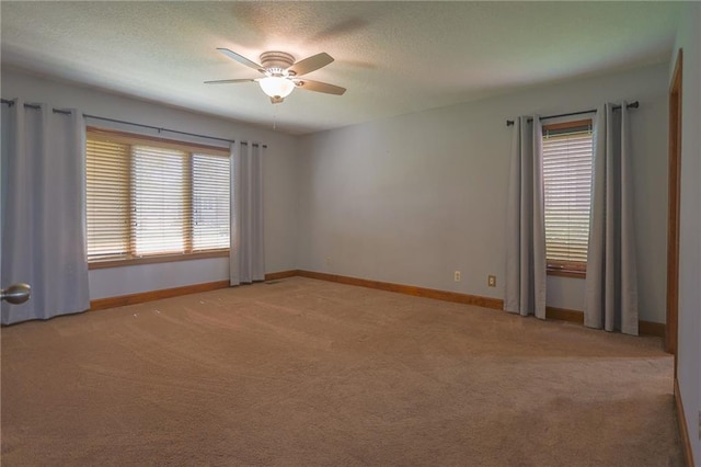 unfurnished room featuring ceiling fan, light colored carpet, a textured ceiling, and baseboards