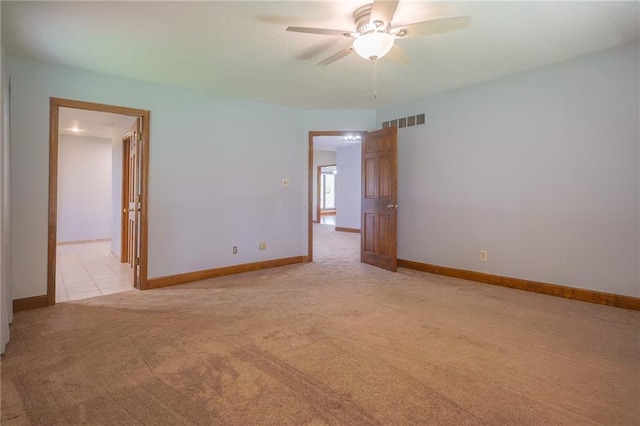 empty room featuring light carpet, ceiling fan, and baseboards