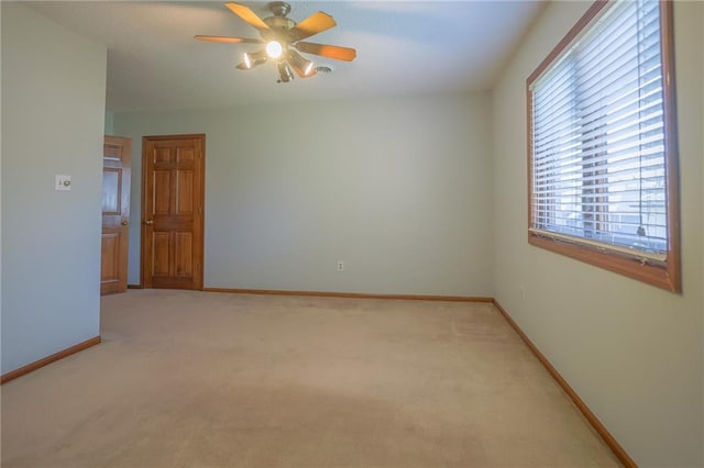 spare room with ceiling fan, light colored carpet, and baseboards