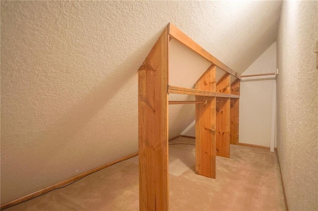 bonus room featuring a textured wall, carpet floors, and vaulted ceiling