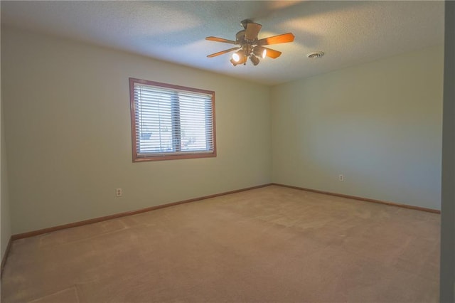 spare room with light colored carpet, a textured ceiling, a ceiling fan, and baseboards