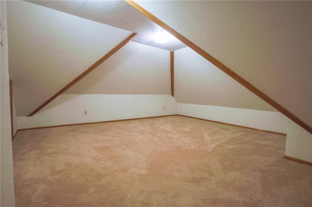 bonus room featuring lofted ceiling, carpet, and baseboards