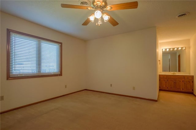 unfurnished bedroom featuring light colored carpet, baseboards, a sink, and ensuite bath
