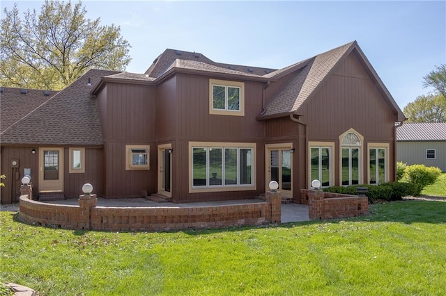 rear view of house featuring roof with shingles, a lawn, and a patio