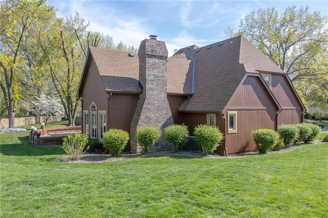 view of side of home with a chimney, a lawn, and a shingled roof