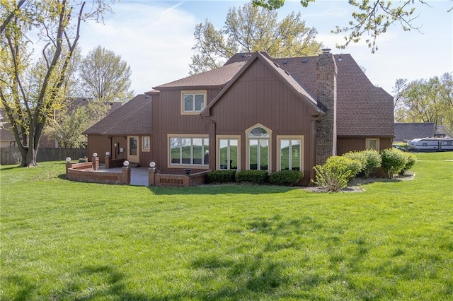 back of house with a chimney, a patio area, and roof with shingles